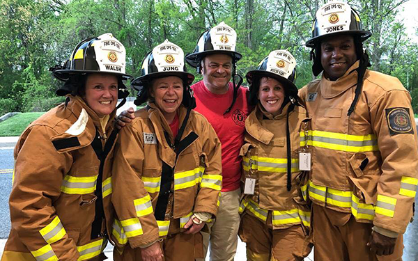 Council members posing for a photo in firefighter gear